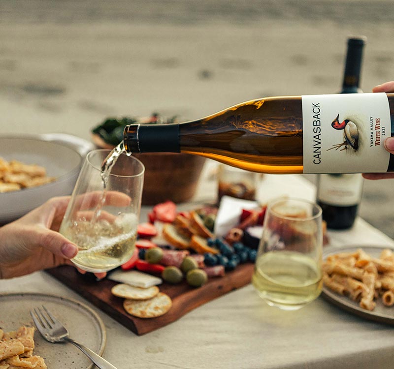Couple pouring Canvasback White wine on the sand