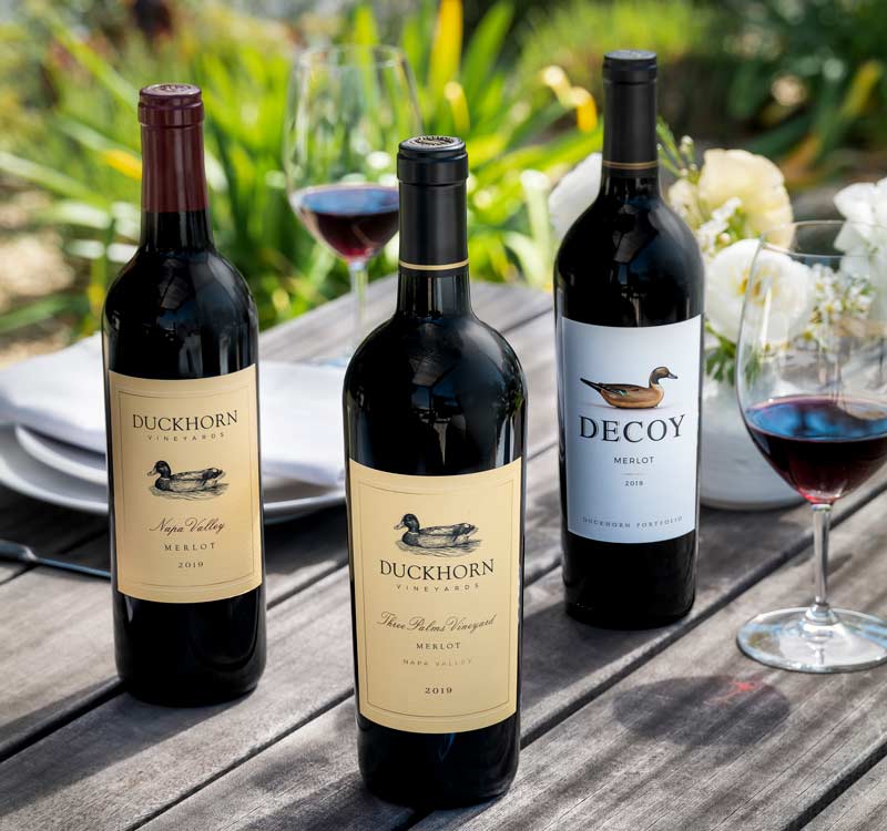 Three bottles of The Duckhorn Portfolio Merlot on an outdoor table