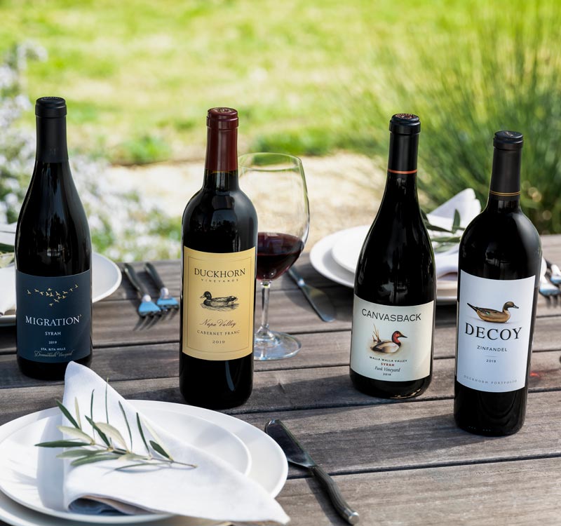 Four bottles of Duckhorn Portfolio red wines on an outdoor table