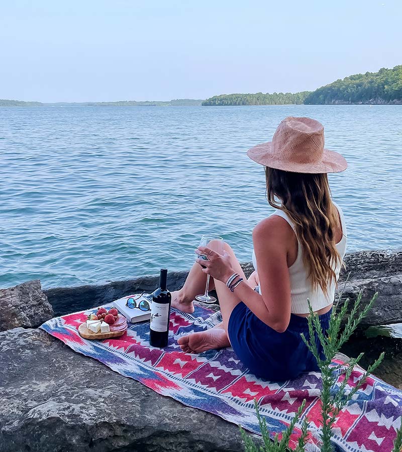Woman with Paraduxx Red Blend wine on rocks at the ocean