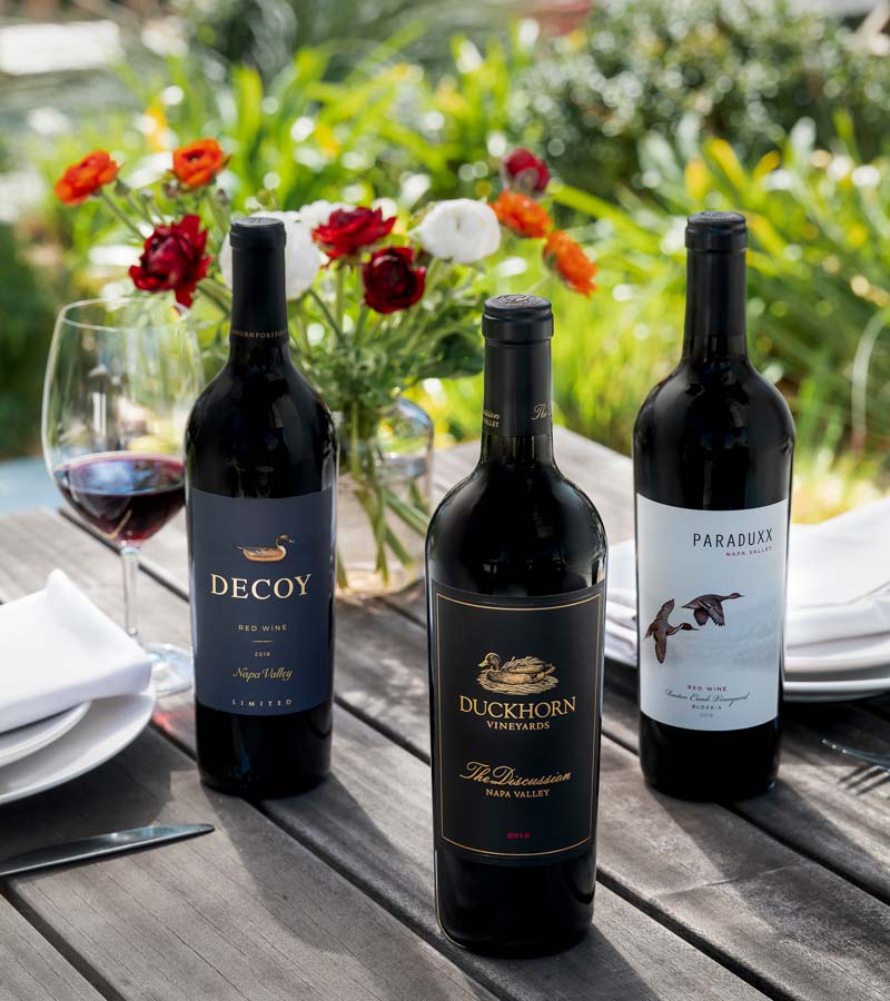 Four bottles of Duckhorn Portfolio Red Wine on an outdoor table