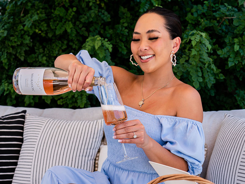 Women on patio pouring Migration Sparkling Wine